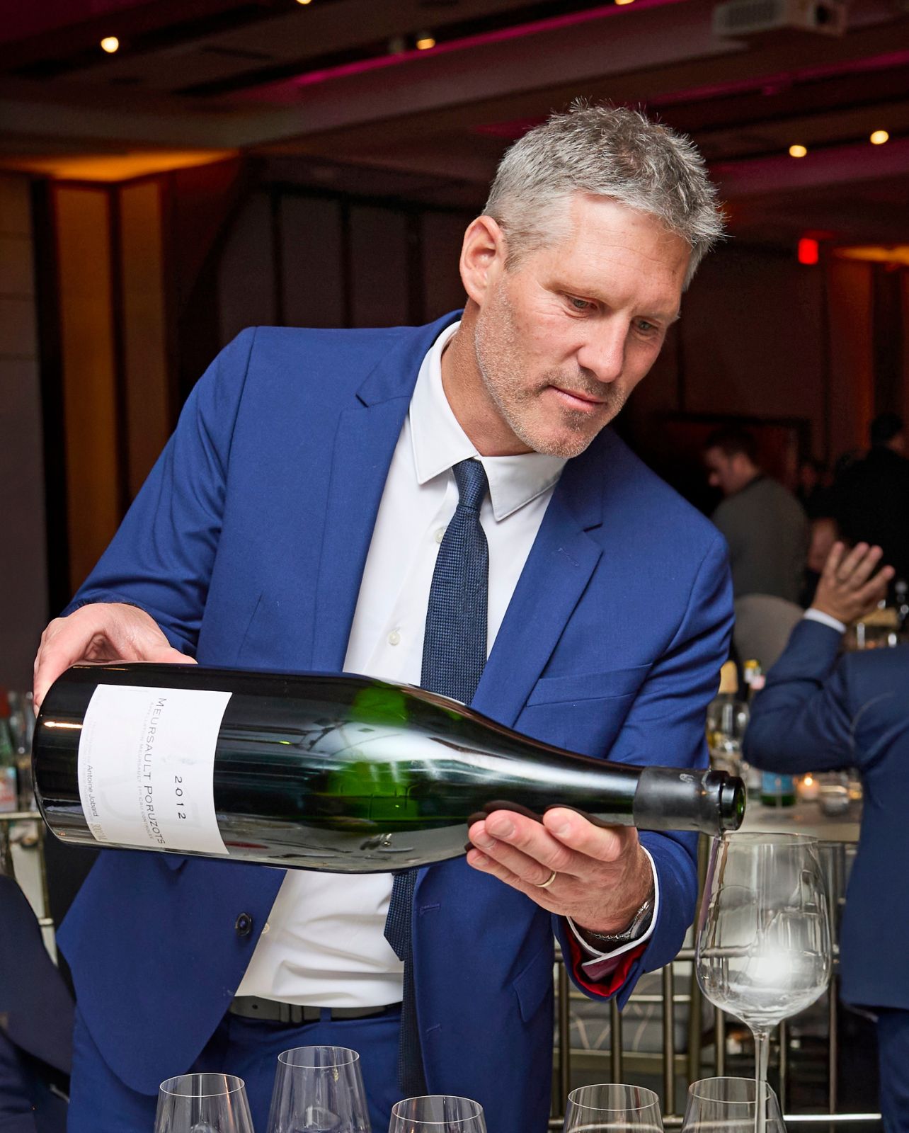 Paulée de Meursault President Antoine Jobard pouring a large bottle of wine into a glass