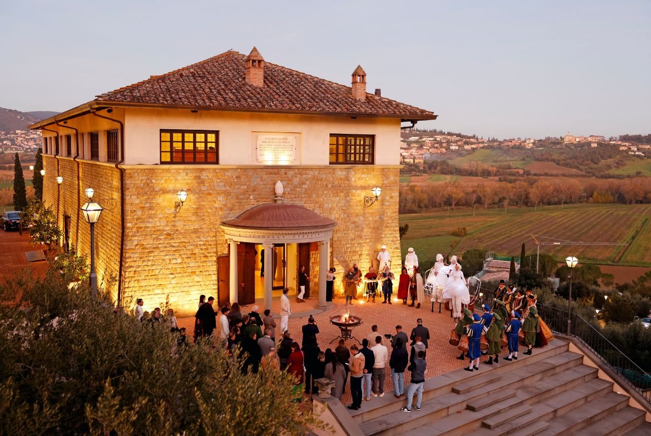 Outside Castello di Solomeo, guests gather around a fire while live musicians play during the arrival
