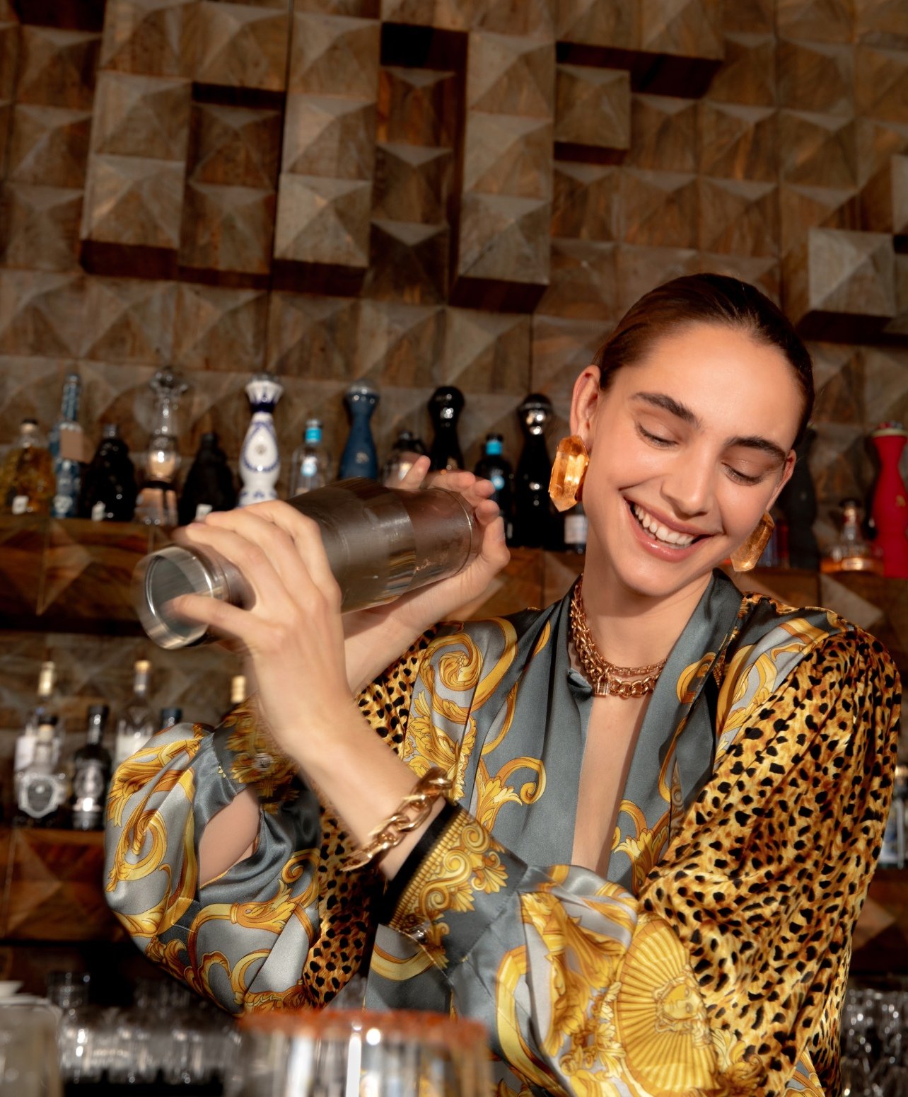 Fashion model mixing drinks at a bar with a silk animal print top