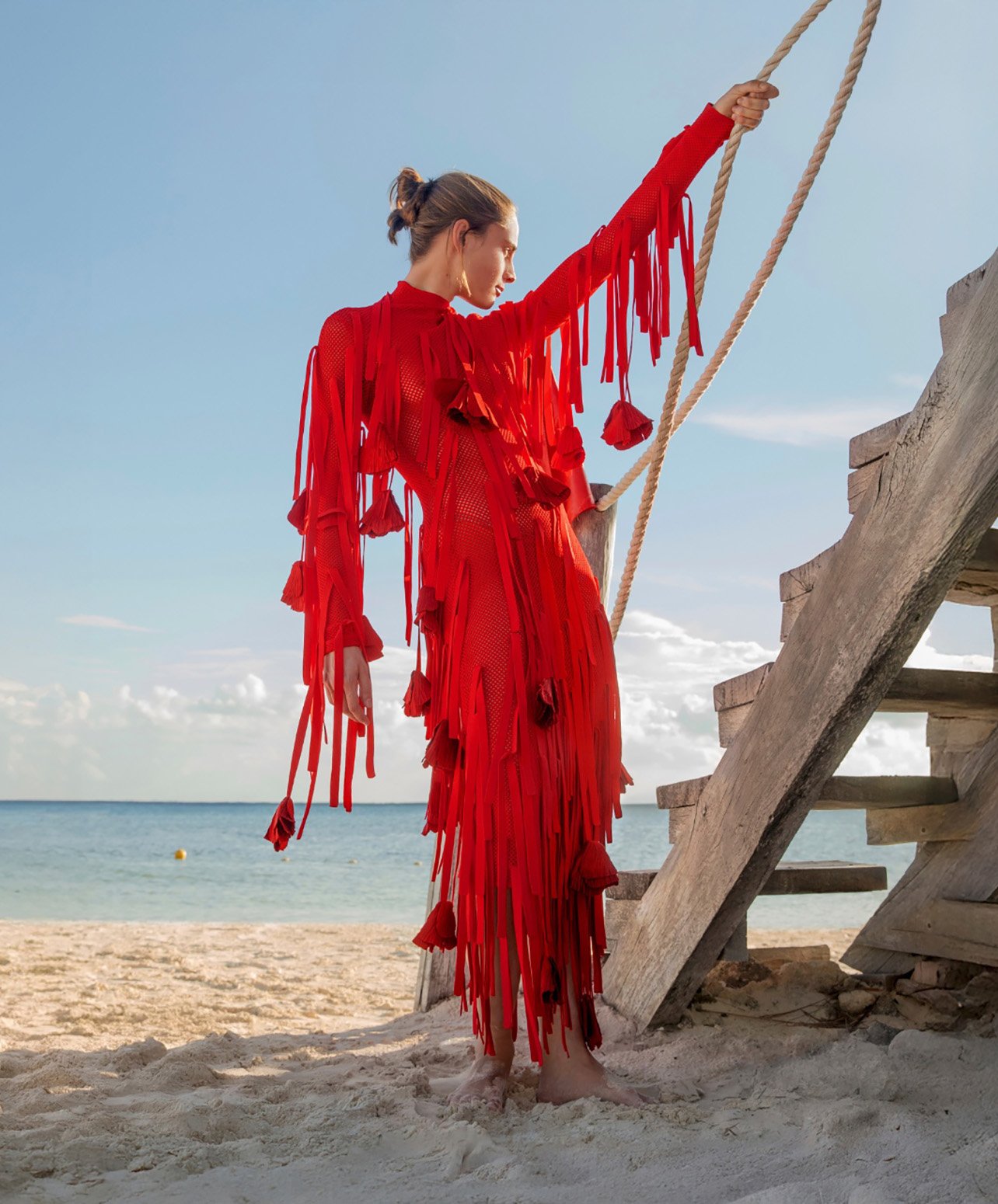 Fashion model on beach with a long red fringe dress