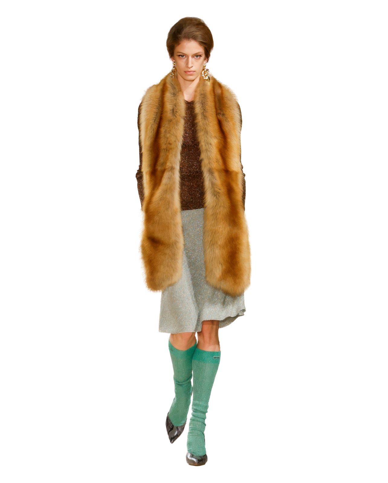 Runway model in a long fur scarf draped over a top and skirt, styled with tall socks and heels