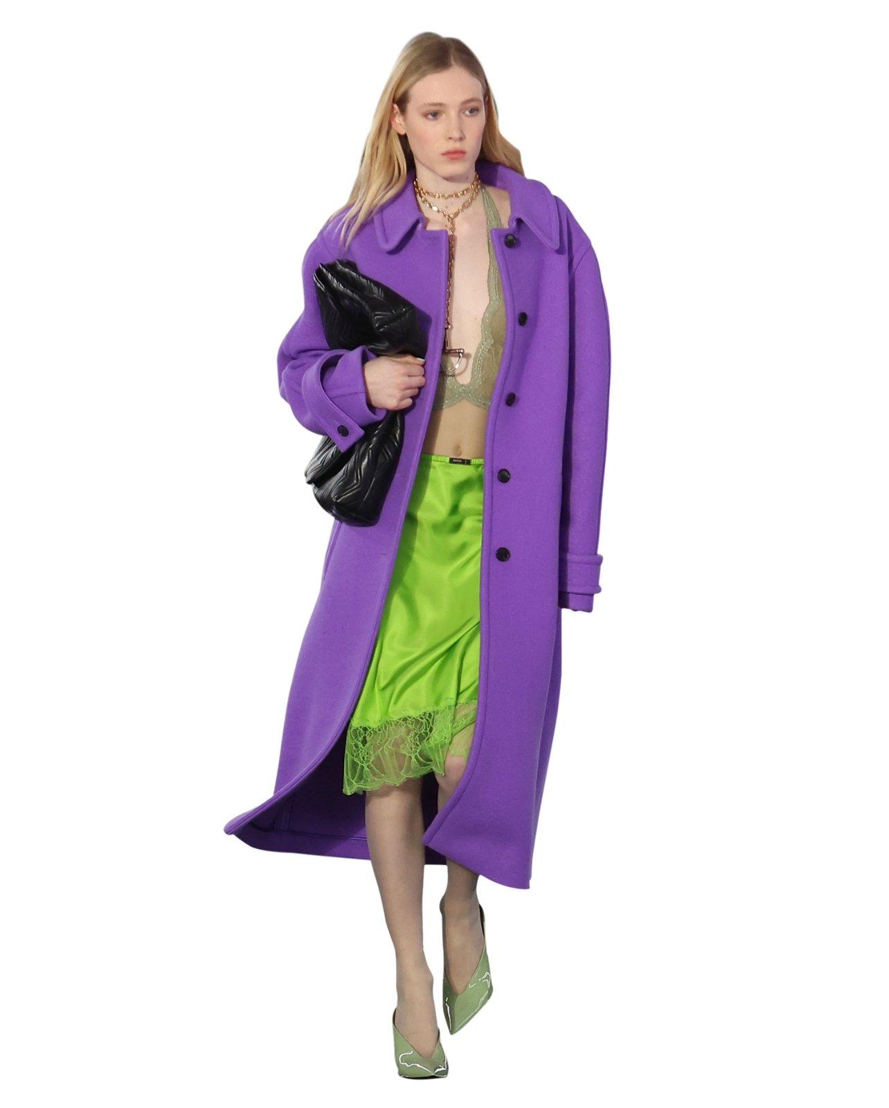 Runway model wearing a bright green silk skirt, purple jacket, and black purse