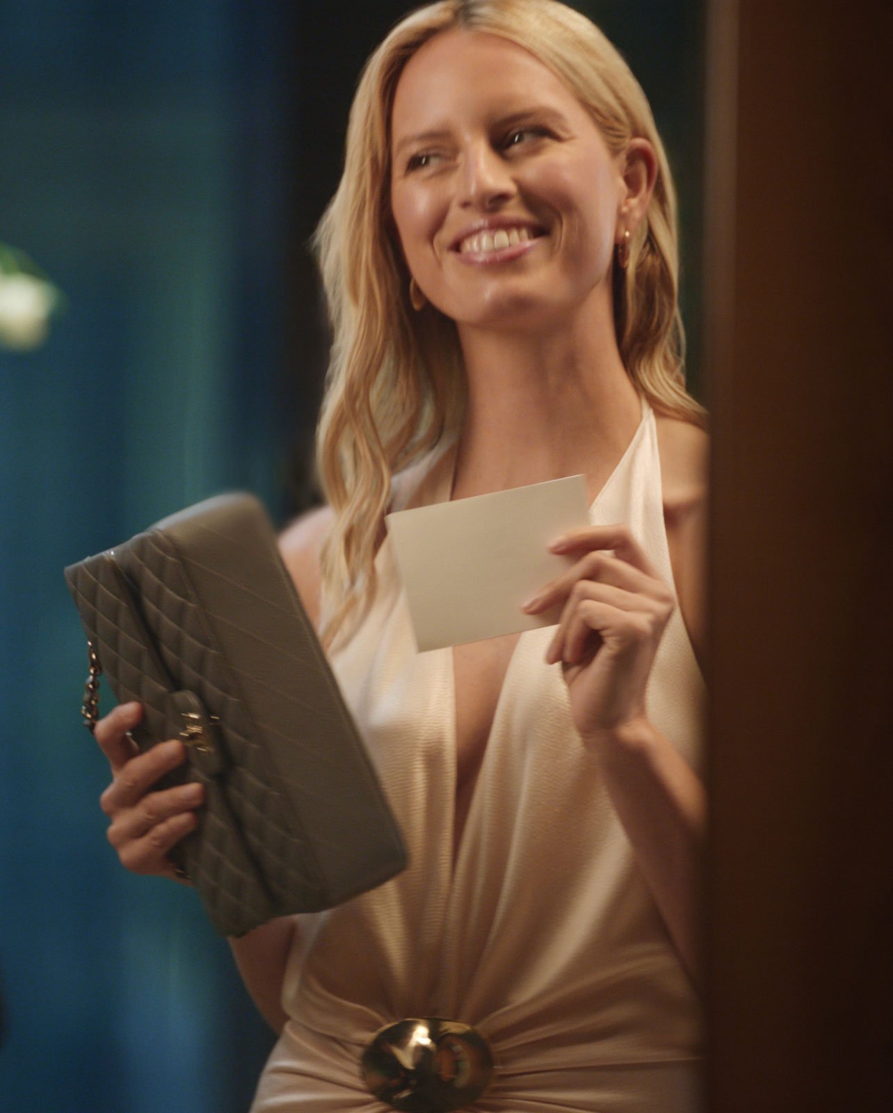 Model wearing a black clutch and notecard in hand