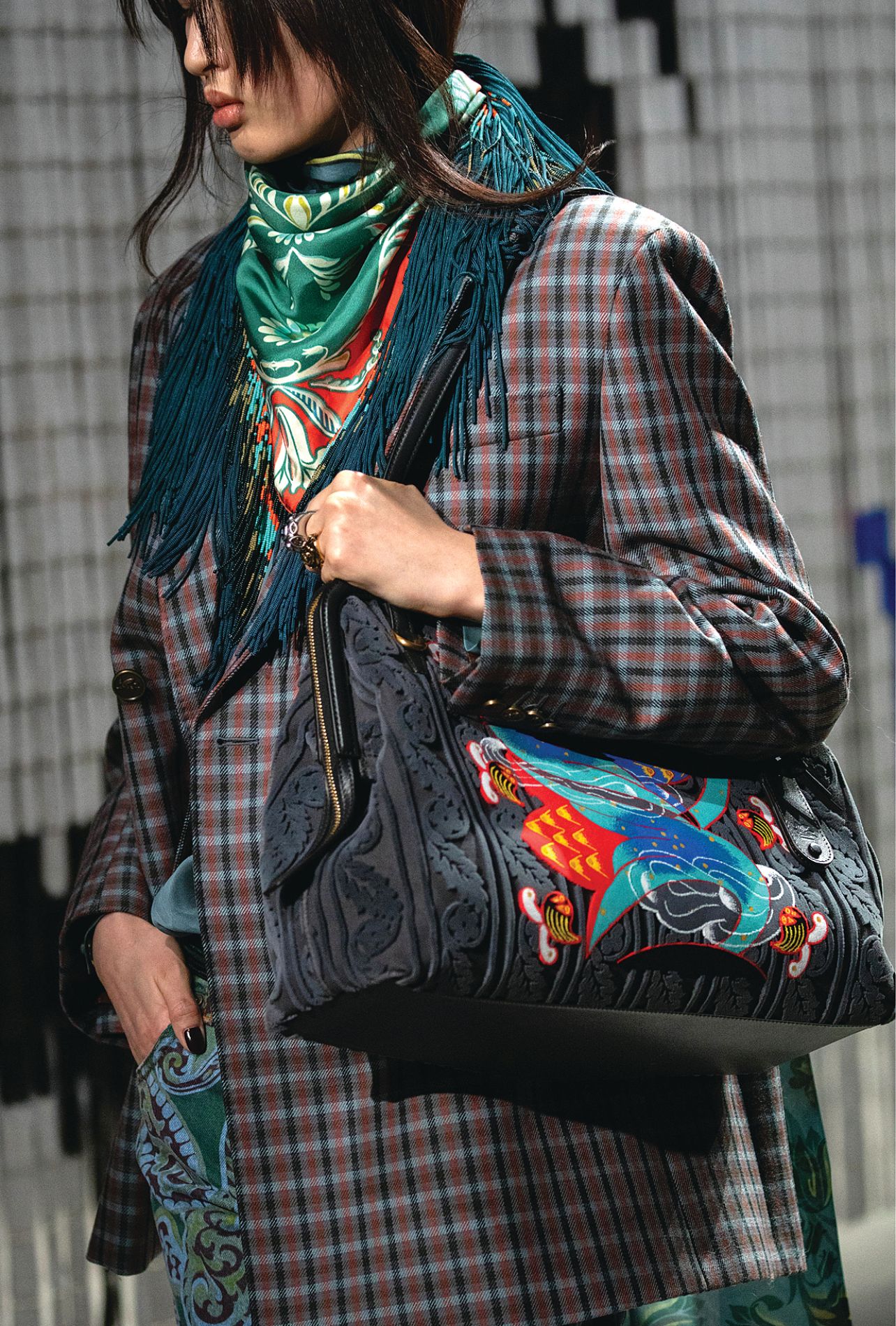 Etro runway model wearing a plaid blazer, silk fringe scarf, paisley pants and a colorful statement purse