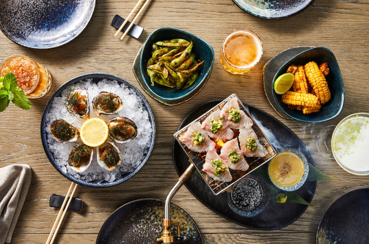 Plates of seafood dishes and snacks displayed on a wooden table at a restaurant