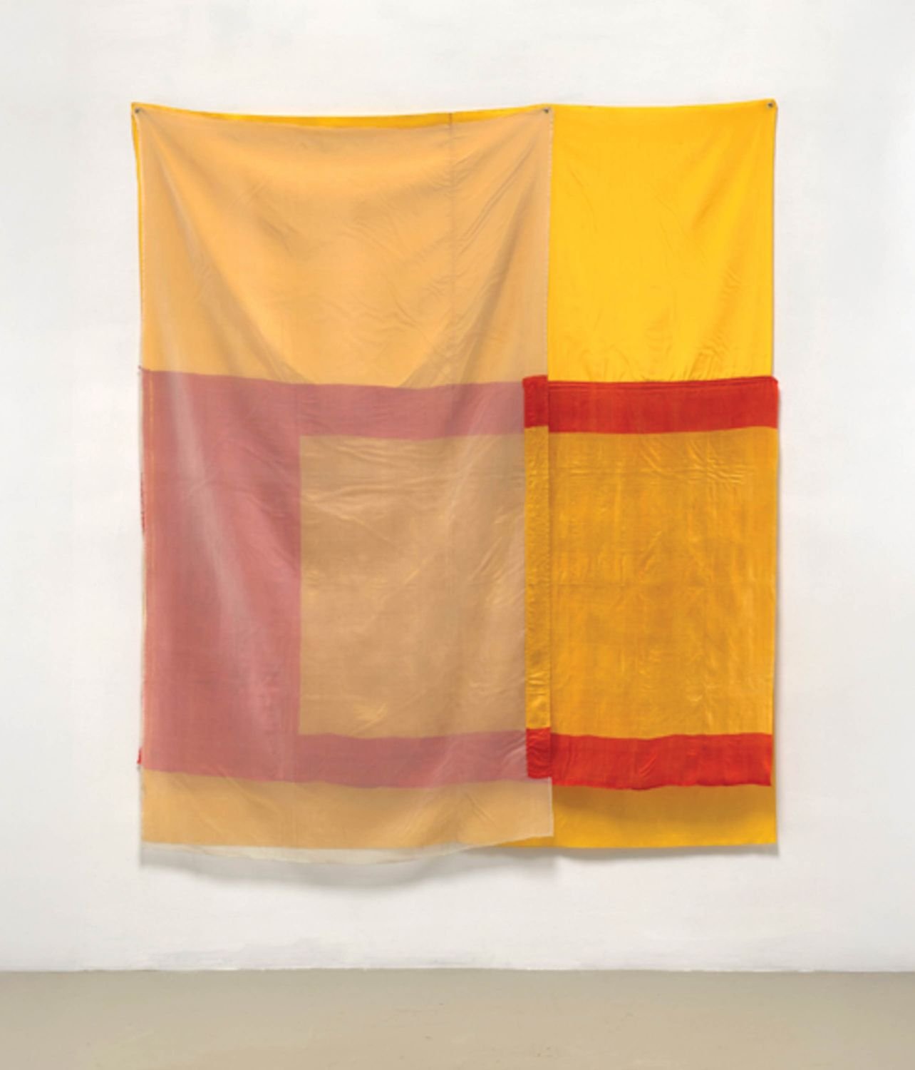 A Robert Rauschenberg fabric works hung in the studio with red, yellow, and orange colors