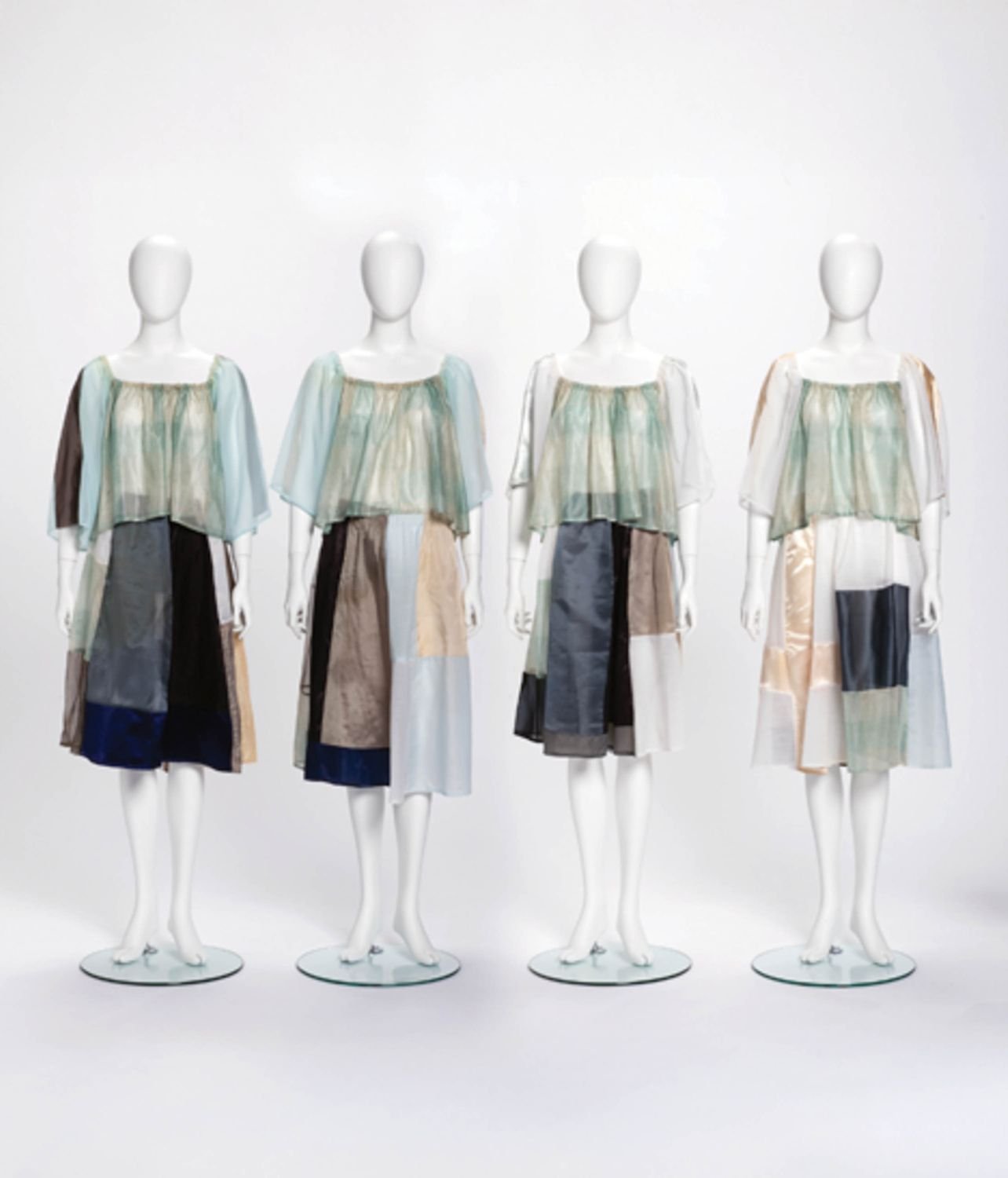 Four dressed mannequins on display in a studio with matching patchwork outfits