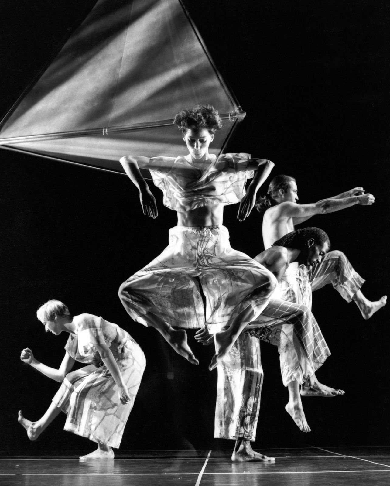 A black and white photo of a dance performance with four artists on stage