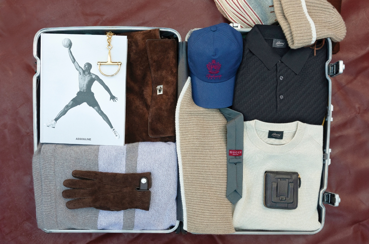 A still-life photo of a suitcase filled with clothes and accessories