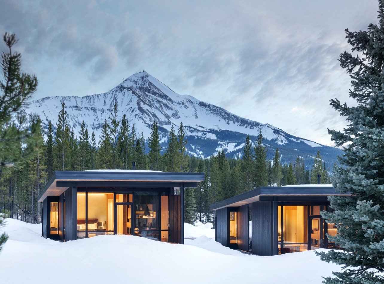 Cabins sitting in the snow with mountains in the background