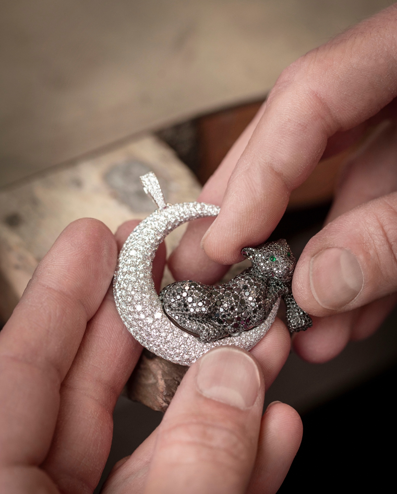 Hand putting together diamond moon and black diamond jaguar jewelry piece