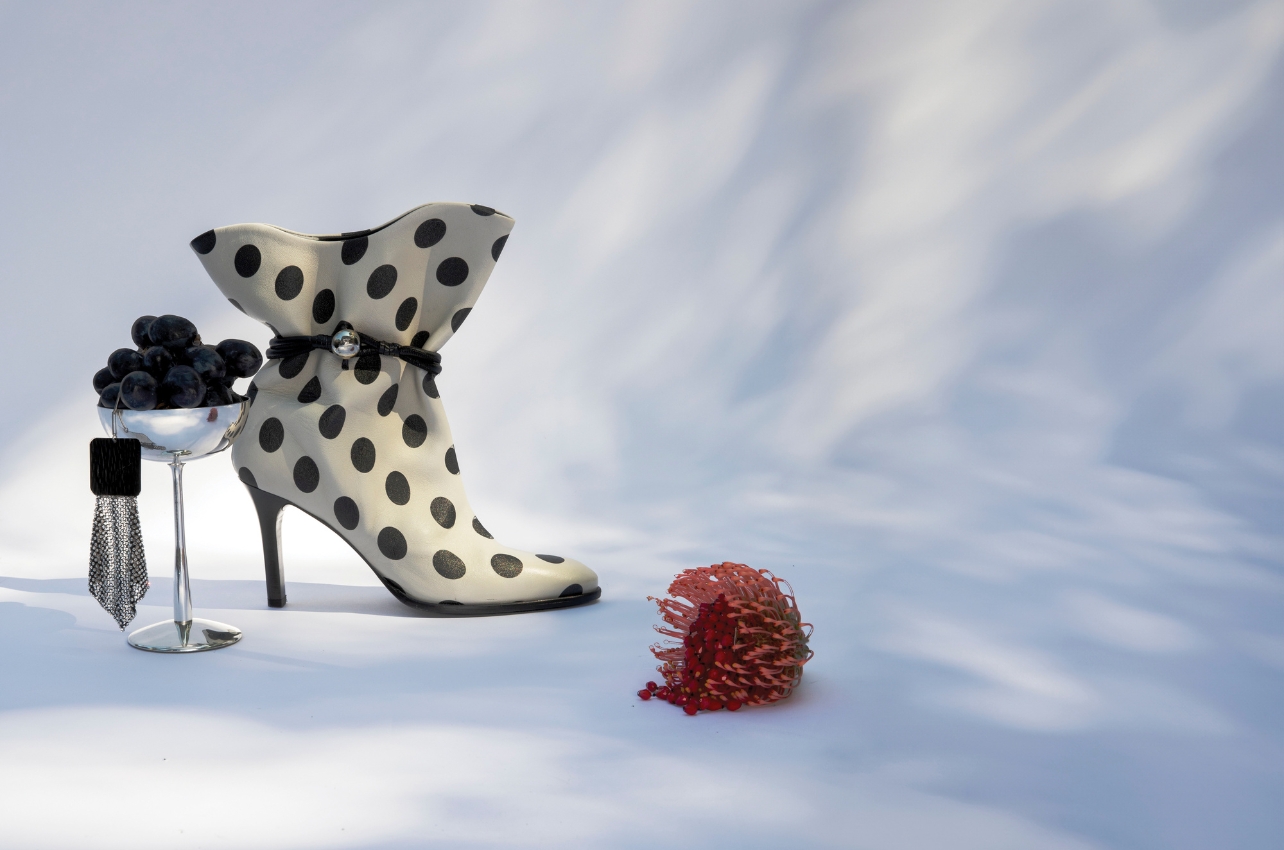 Polka dot boots, a silver cup and black and silver earrings photographed in a still life photo