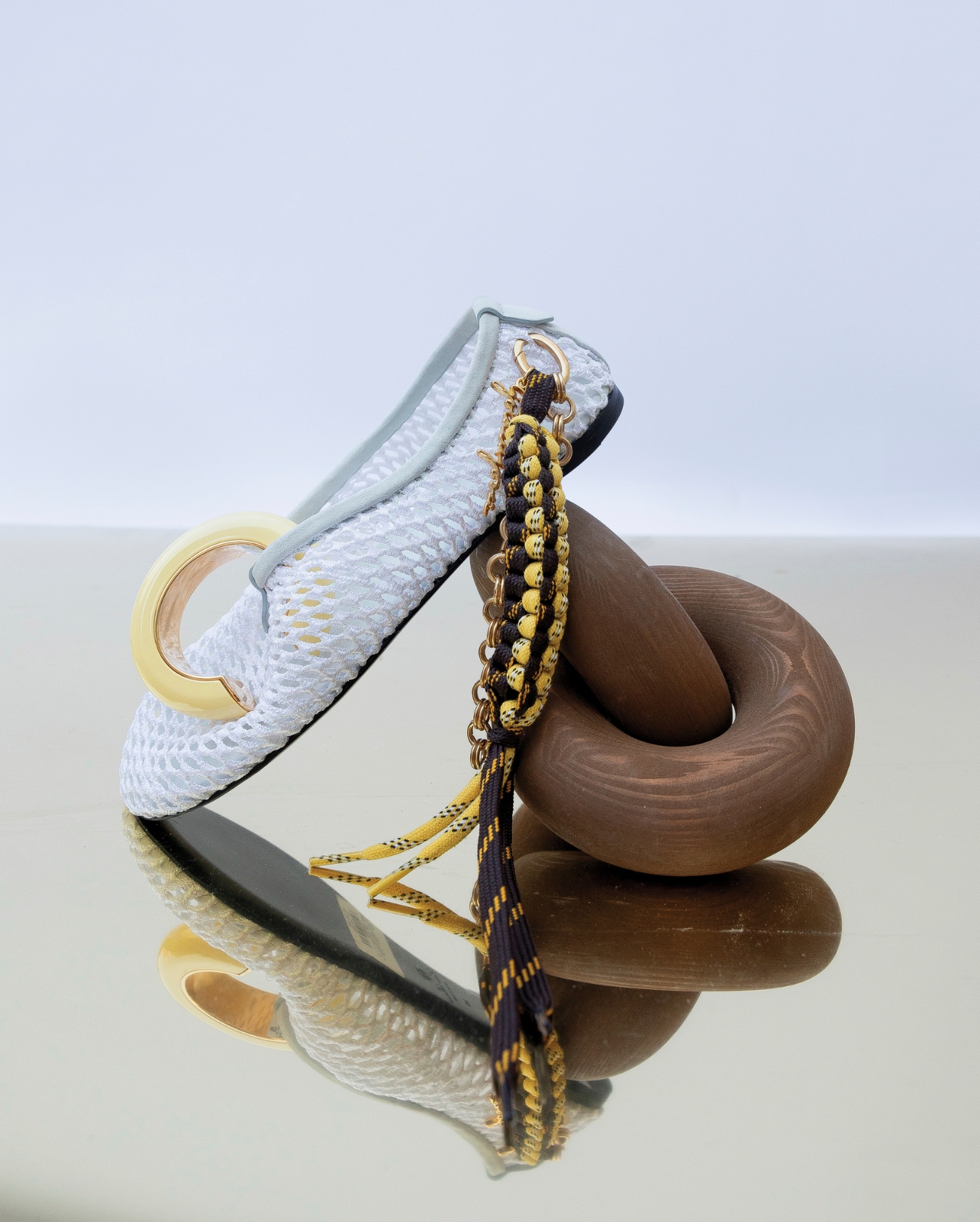 A pair of loafers and a gold cuff and a charm photographed in a still life photo