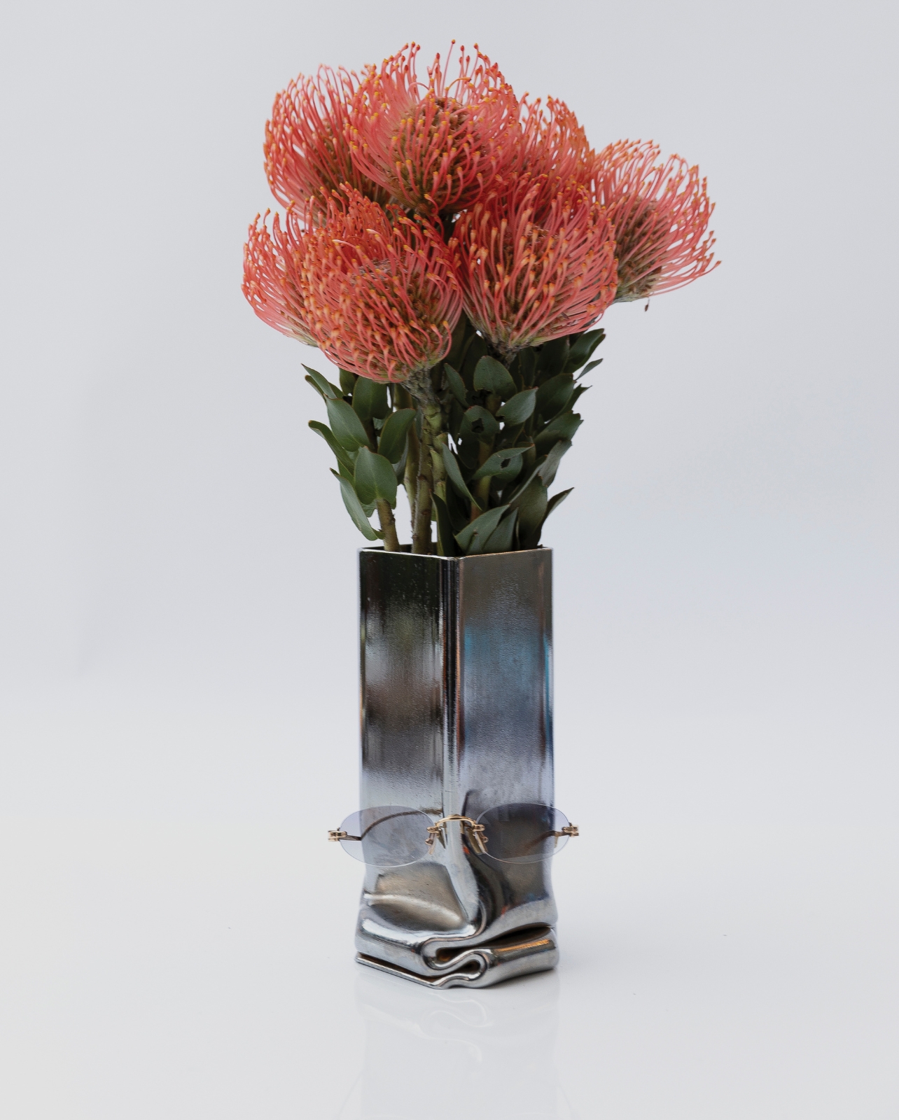 Miu Miu sunglasses photographed on a vase with orange flowers