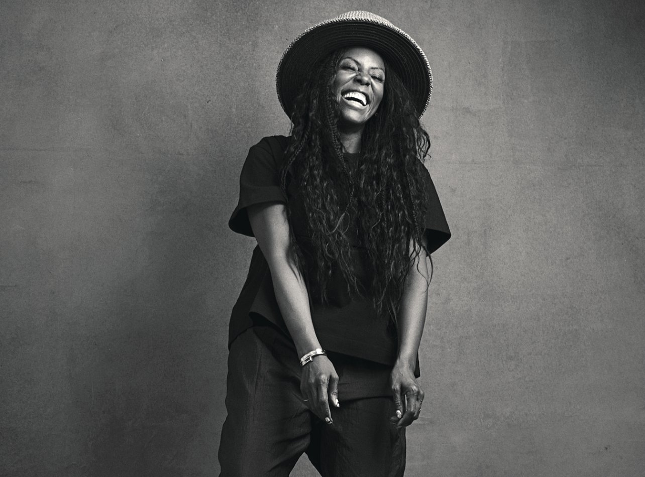 Black and white portrait of June Ambrose laughing in a studio