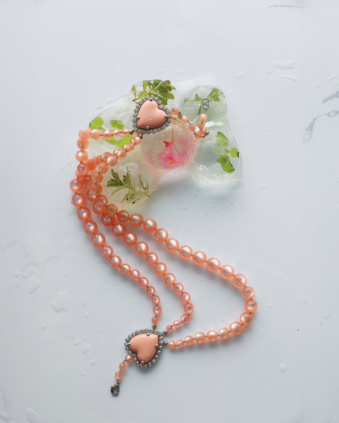 A peachy pearl necklace with a stone heart photographed in a still-life image