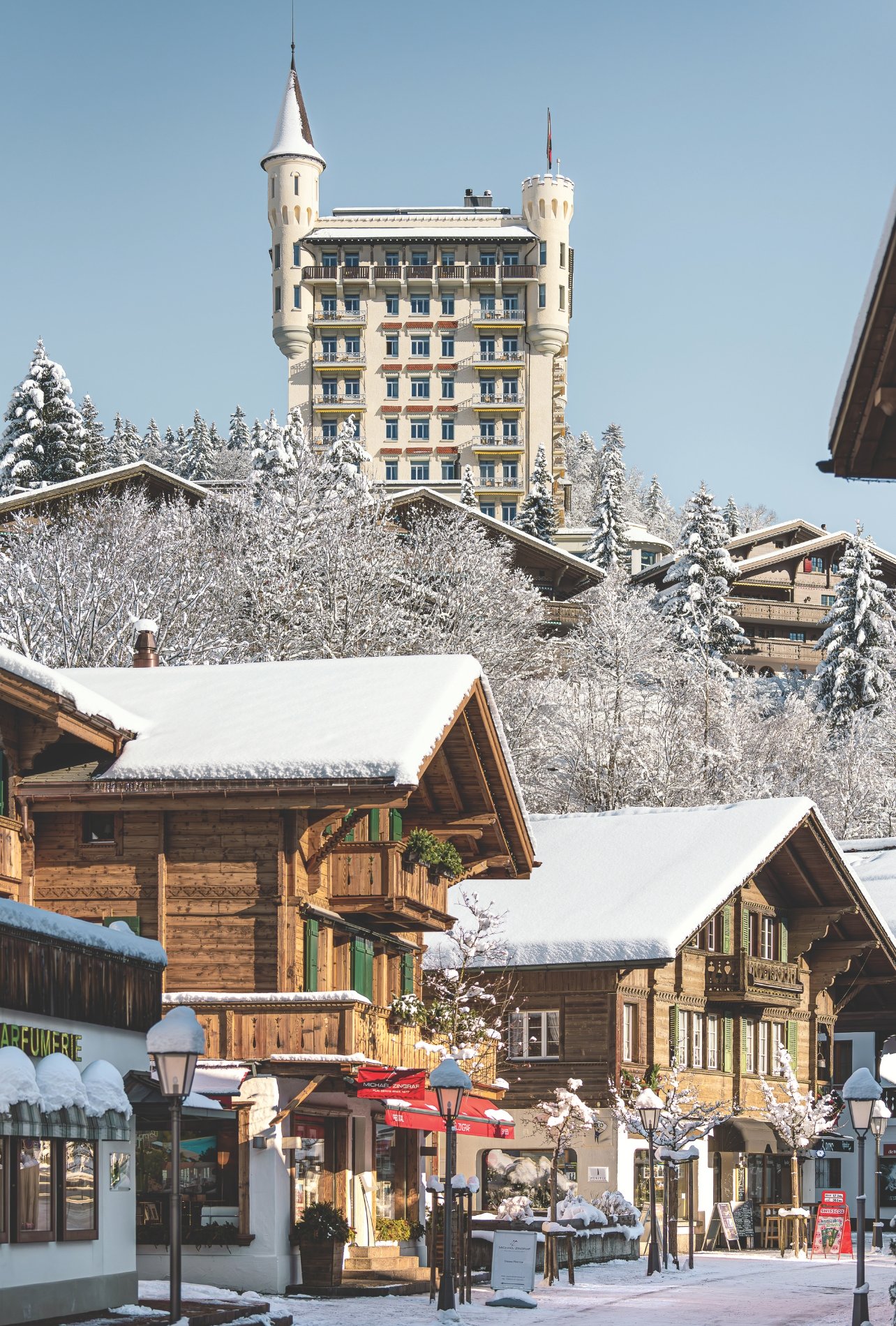 An exterior shot of the Gstaad Palace alongside shops in Gstaad