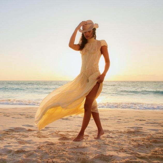 Model wearing a flowy sheer dress and straw cowboy hat
