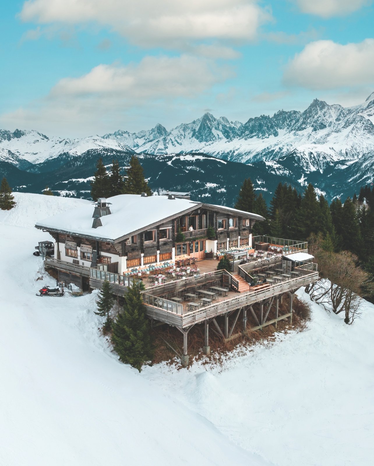 A restaurant with a large outdoor seating deck with mountainous views