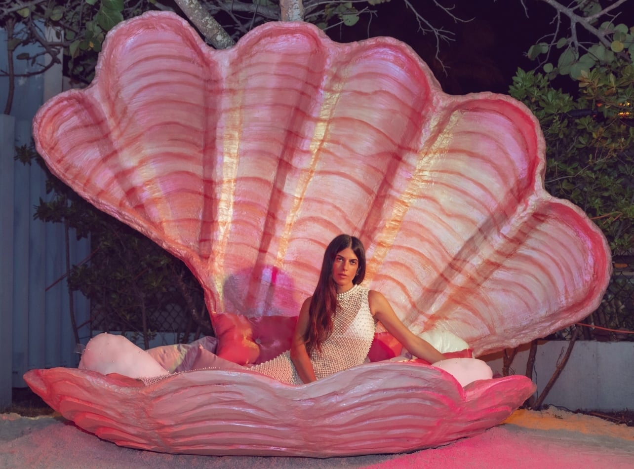 Model Ana Bonamico sitting inside a giant pink clamshell with a long dress on