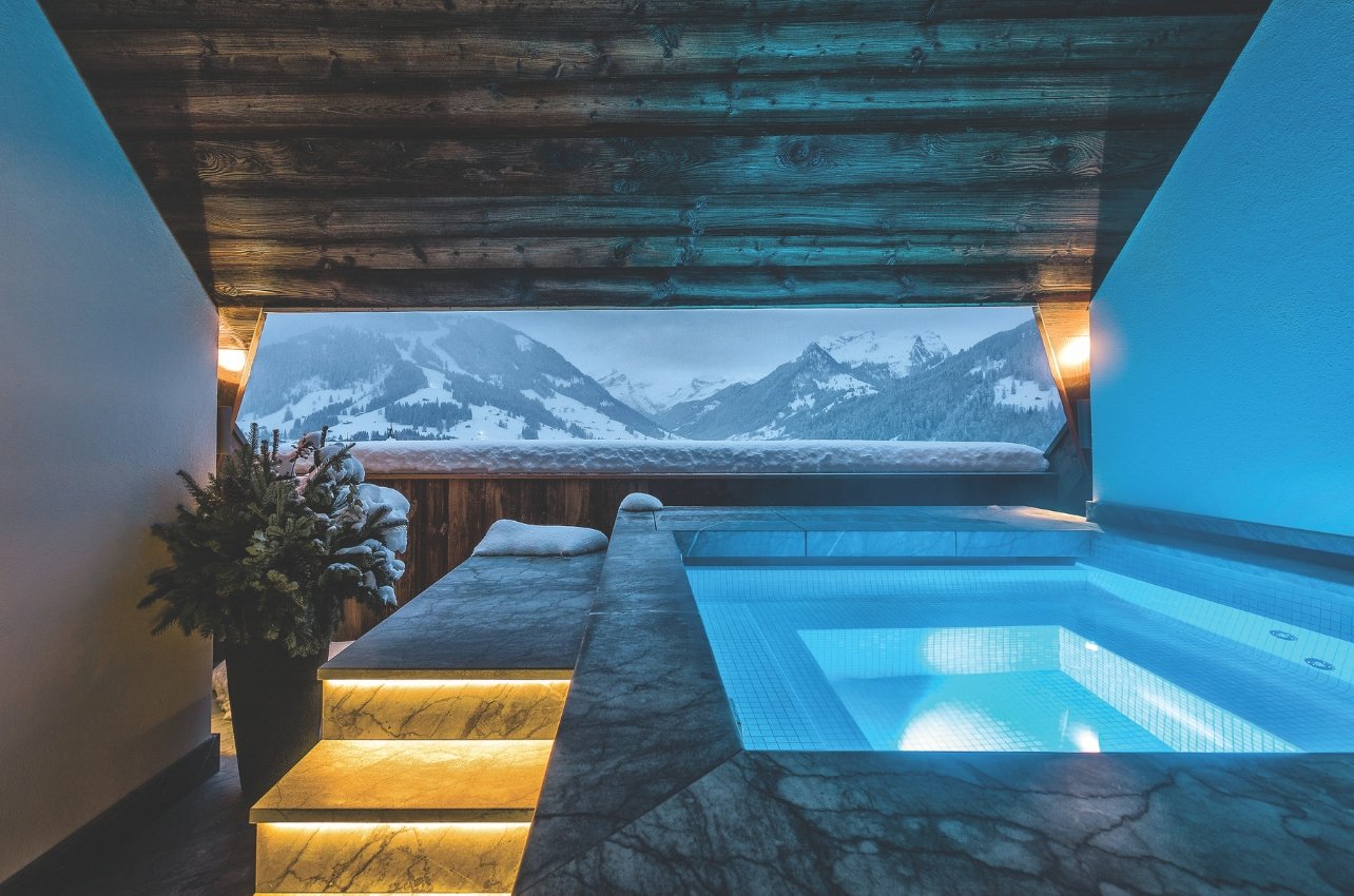 An outdoor jacuzzi with a snowy mountainous scenic view