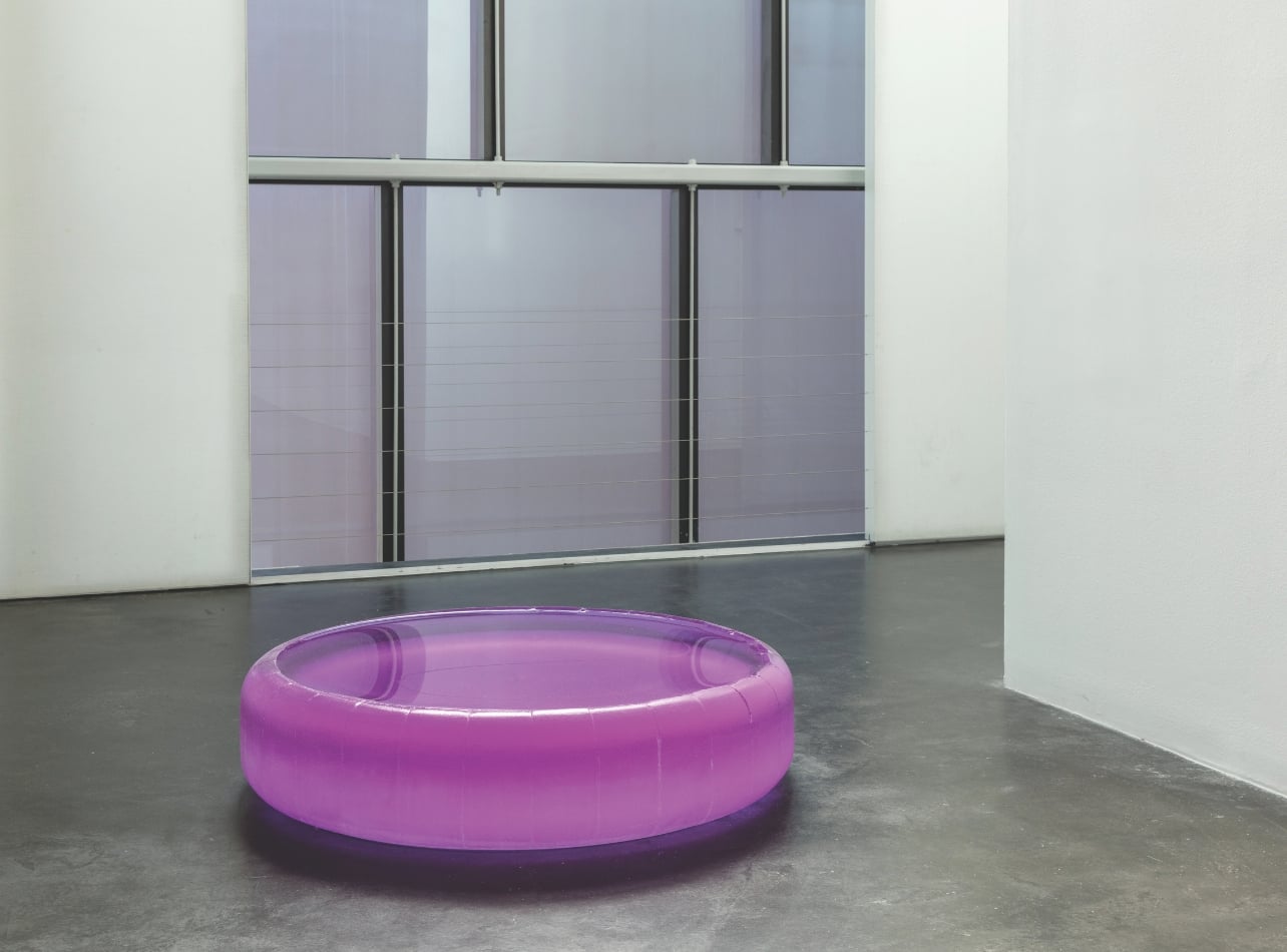 An art installation of a purple pool filled with water in a studio