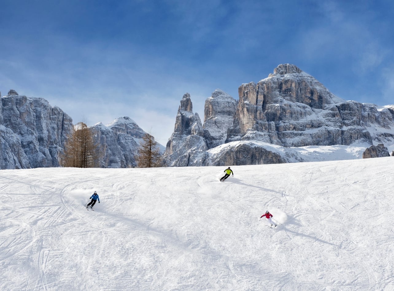 Three people skiing with colorful jackets on a snowy mountain