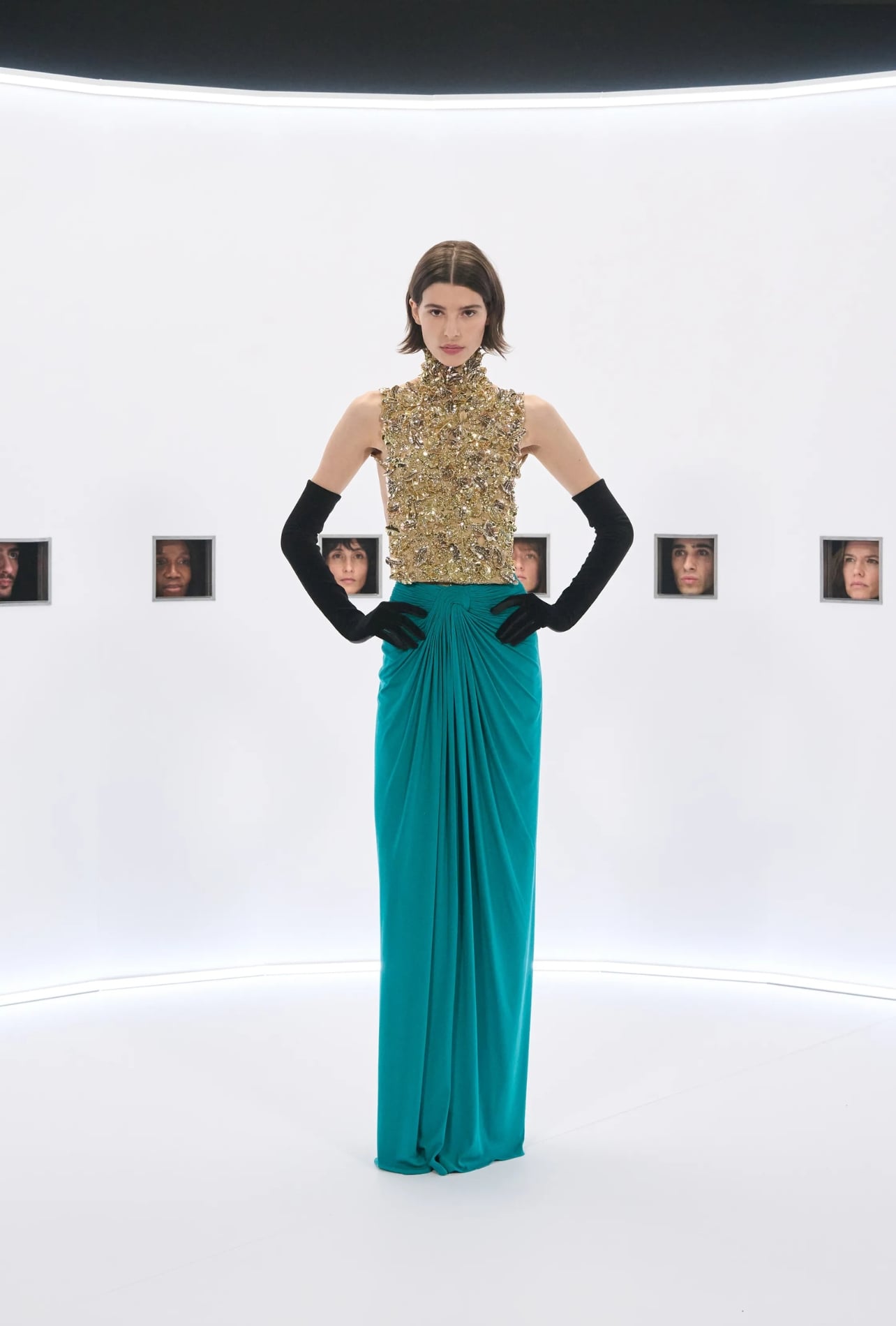 Valentino runway model wearing a gold top and teal skirt with black gloves