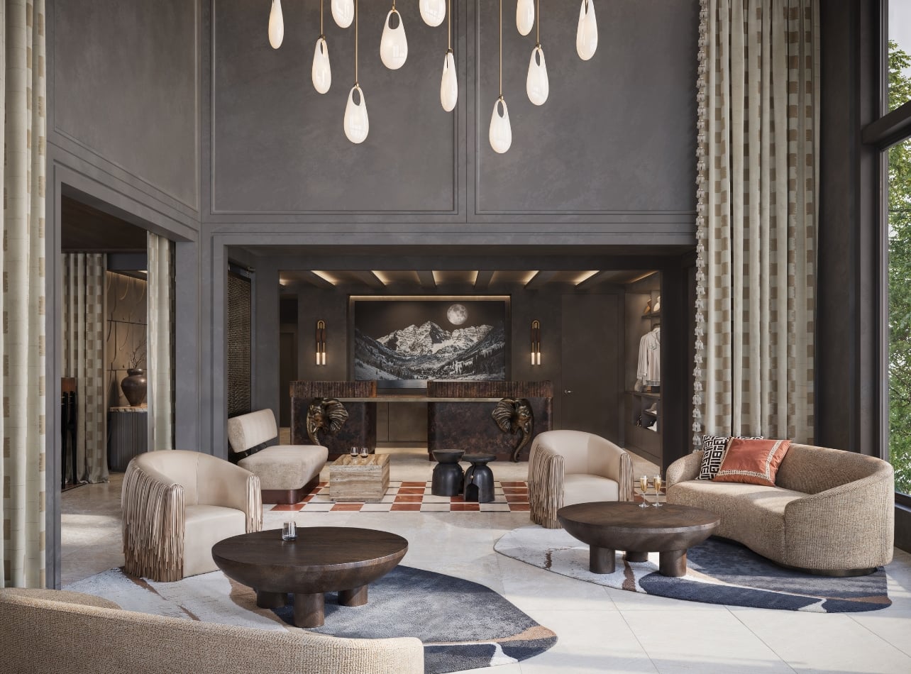 A hotel lobby with tall ceilings, hanging lights, and tan furniture