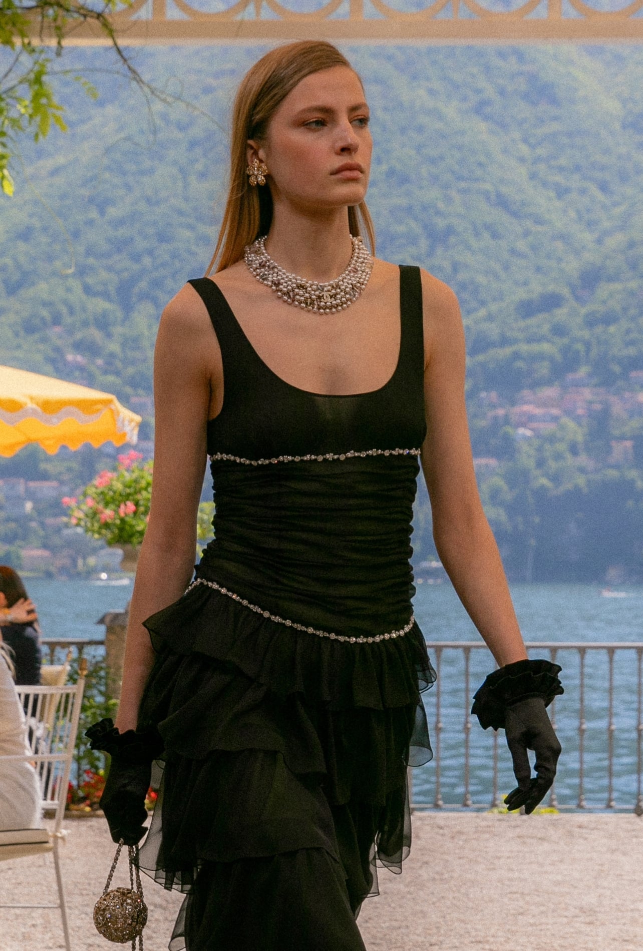 A Chanel runway model wearing a pearl necklace and gloves