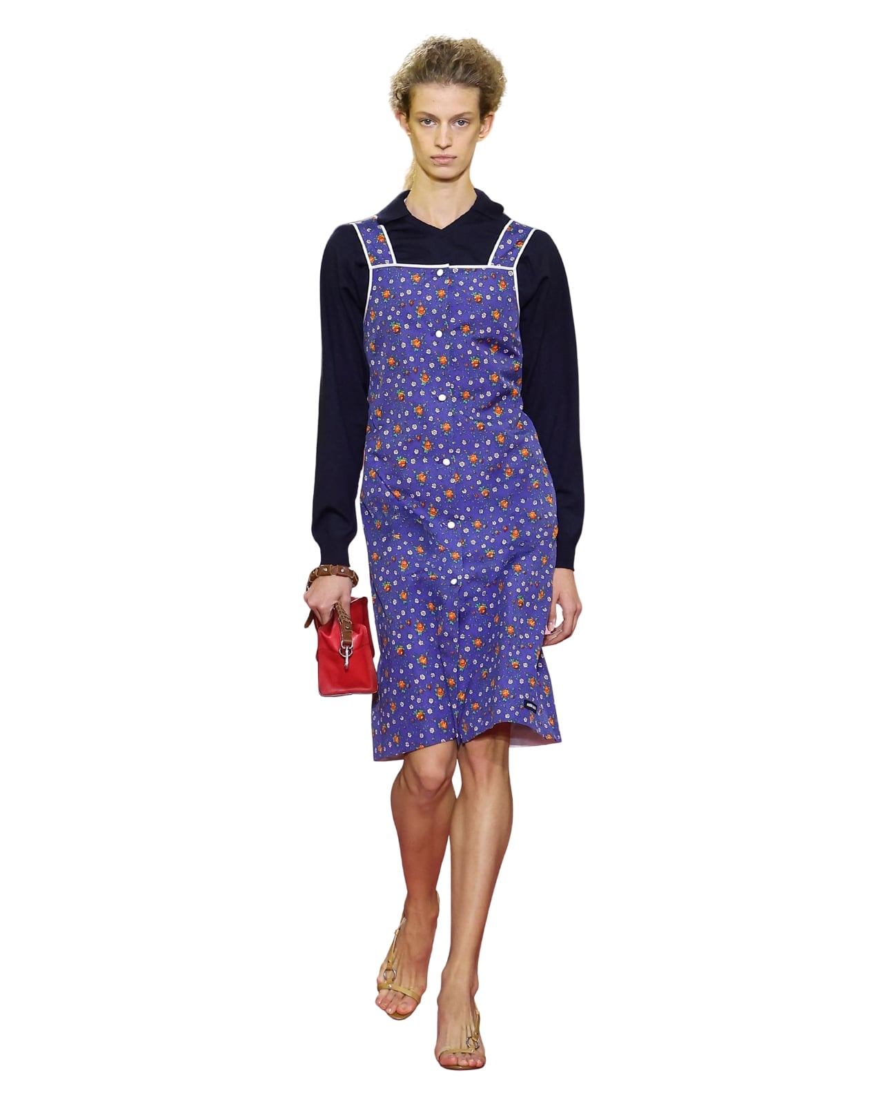 A Miu Miu runway model wearing a floral apron paired with a long sleeve top