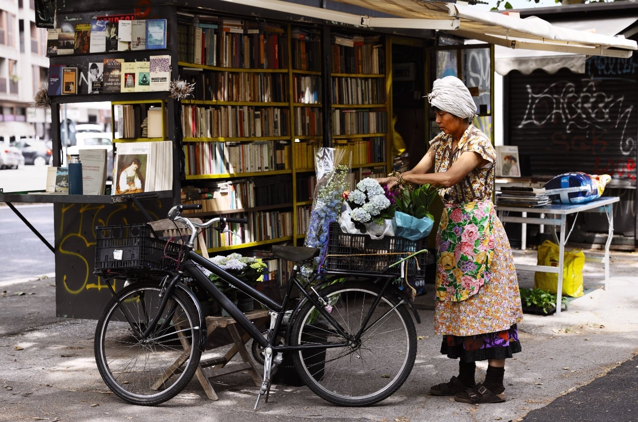 A woman wearing an apron organizing flowers in her bike basket