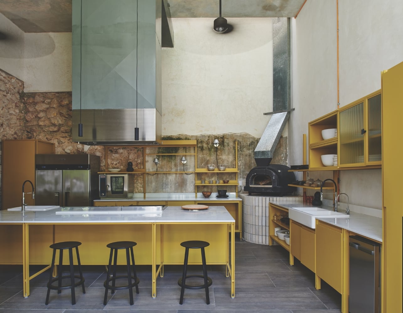 A kitchen with yellow shelves and exposed walls