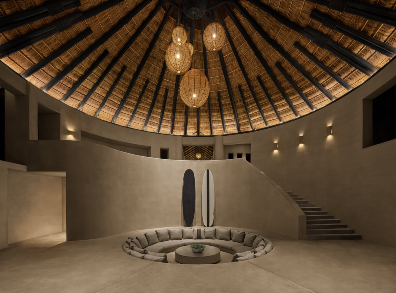 Interior room with a circular couch, hanging lights, and surboards