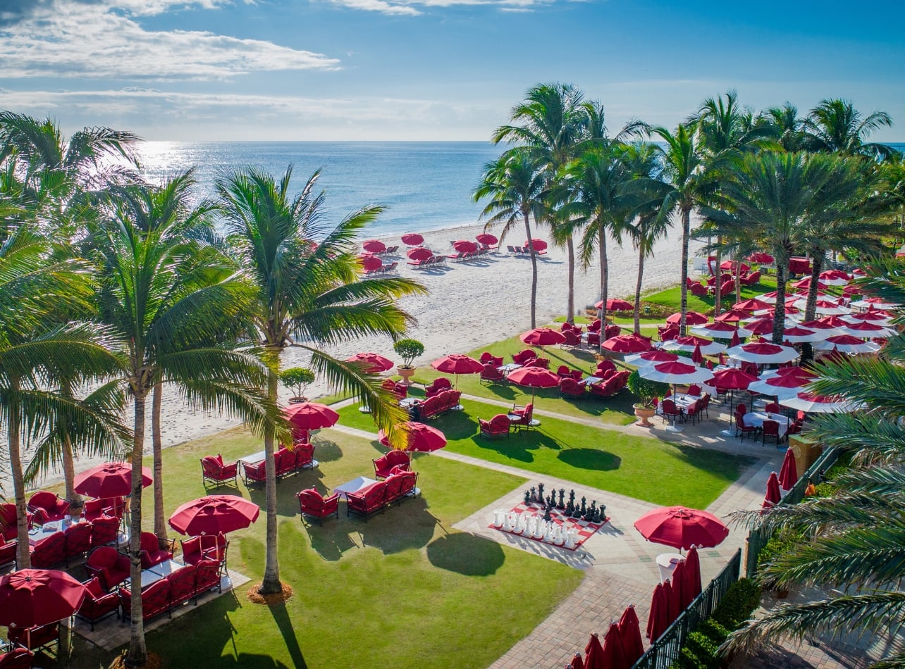 Beach shot of Acqualina with red umbrellas and a large chess game