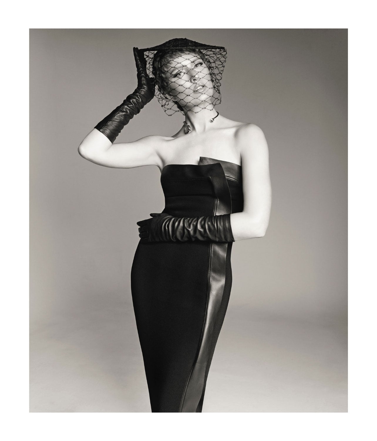 A woman wearing a black leather dress and long leather gloves