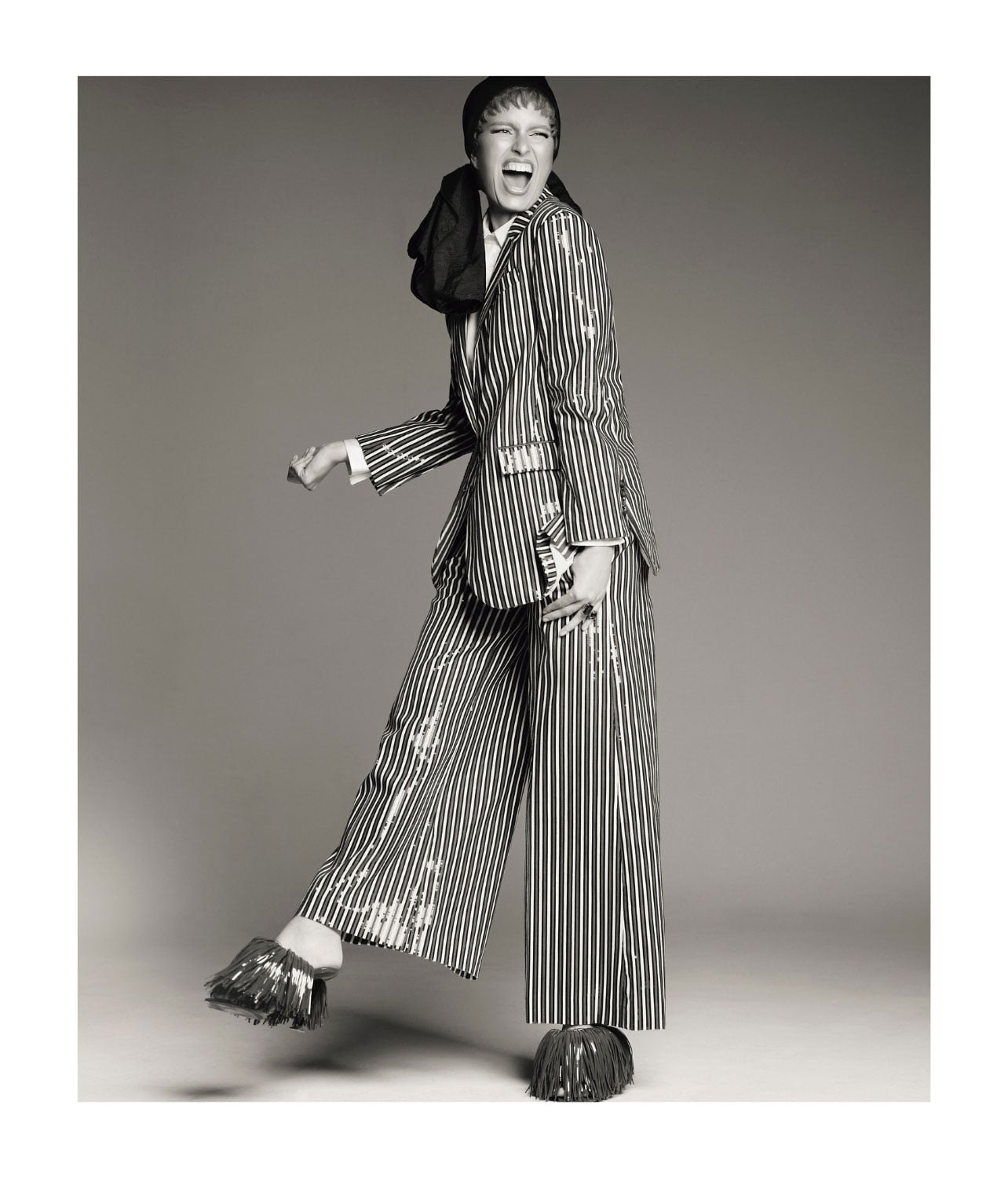 A woman wearing a matching striped pant suit and fringe shoes