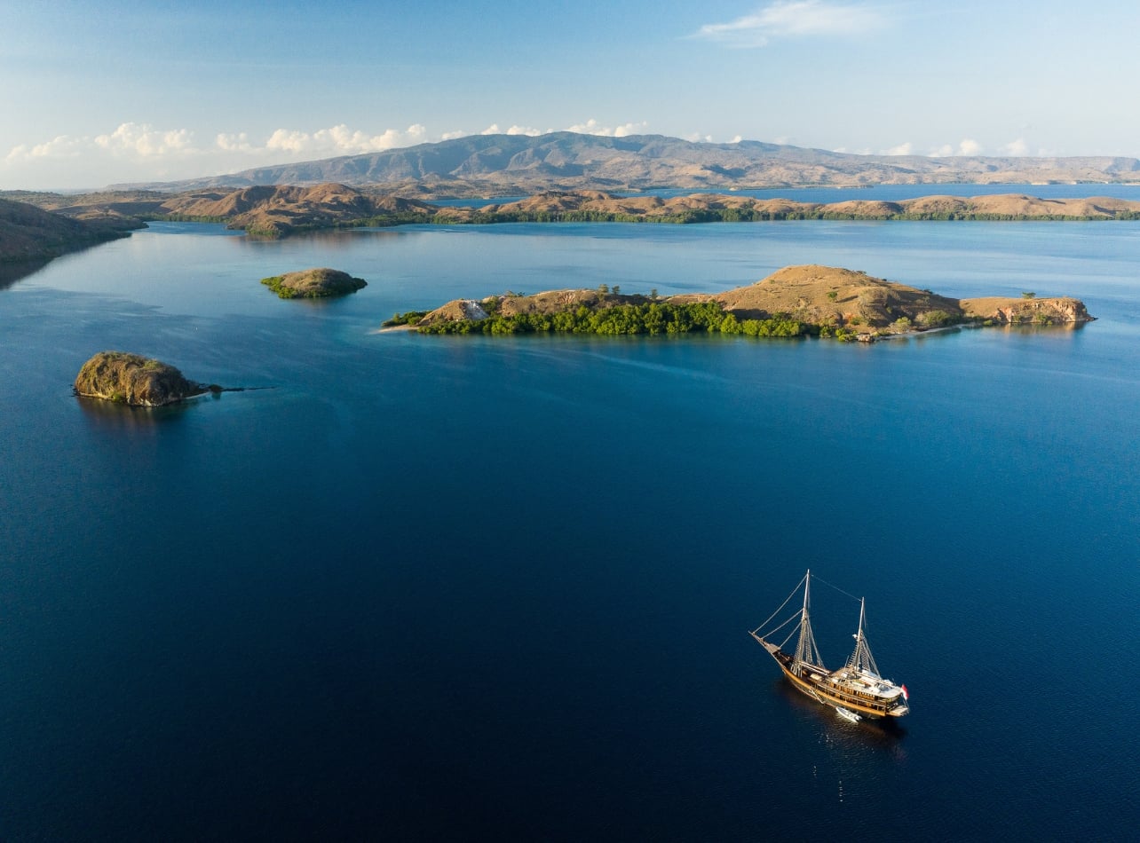 An aerial view of Dania Baru with a charter yacht and view of mountains