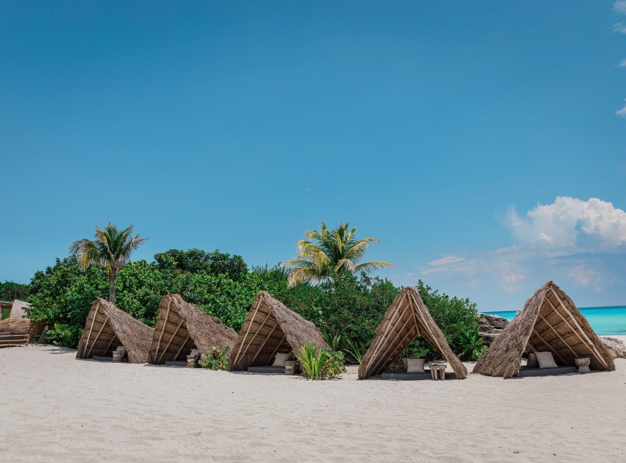 Private hits lining the beach with a blue sky