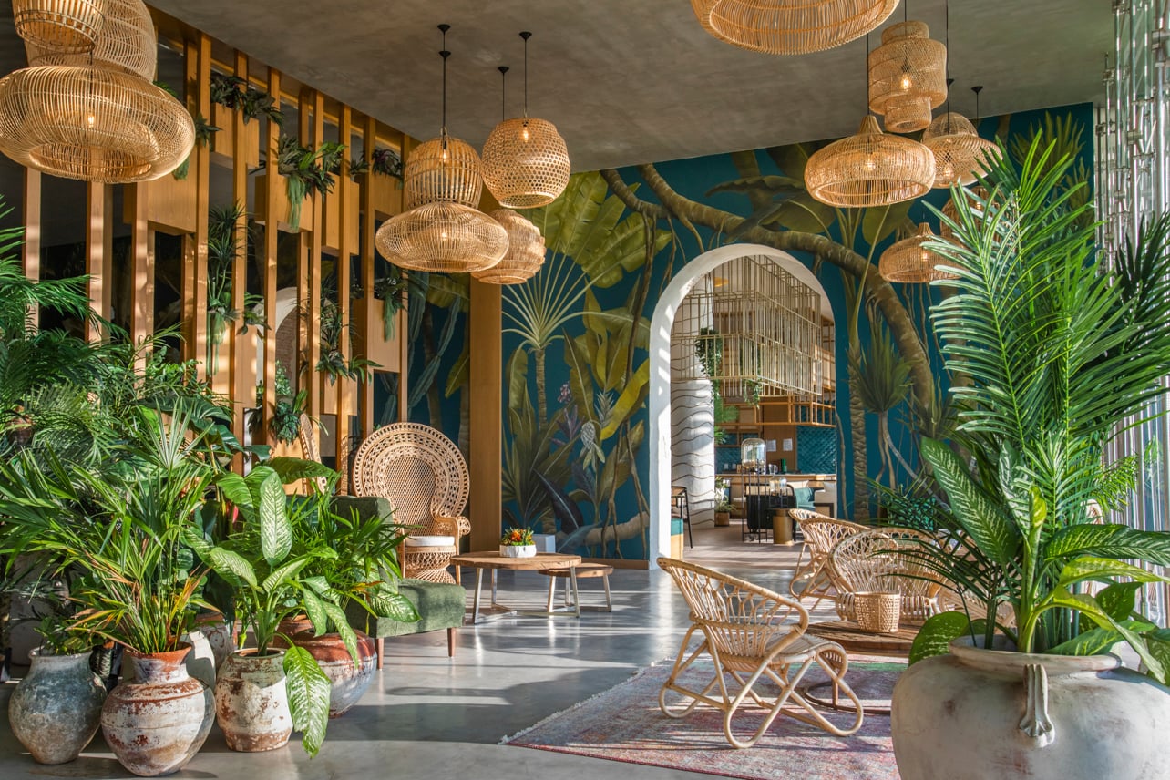 Interior shot of a restaurant with plant murals and live tropical plants