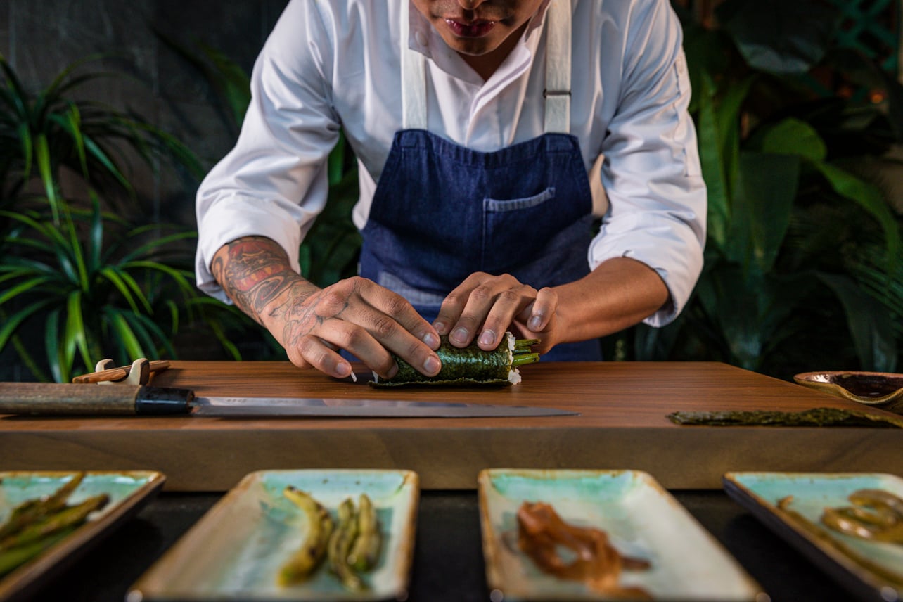 A chef rolling sushi at a restaurant