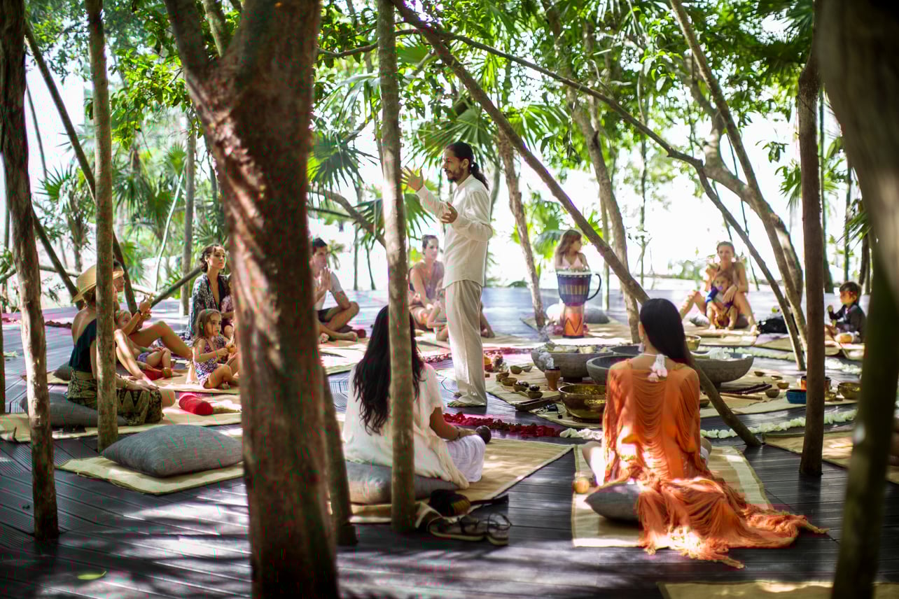 A yoga teacher instructing in an outdoor tropical space