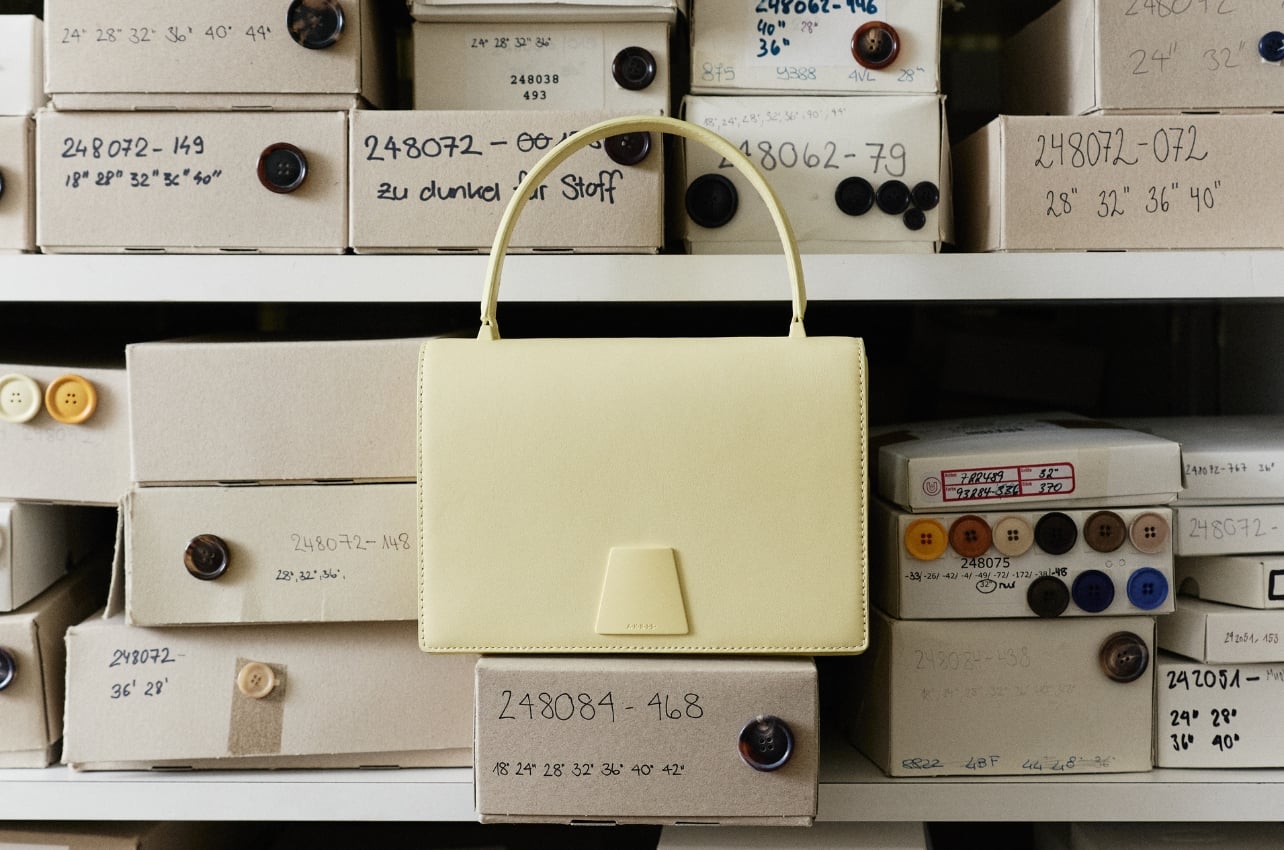 A cream Alice purse in front of stacked labeled boxes of buttons