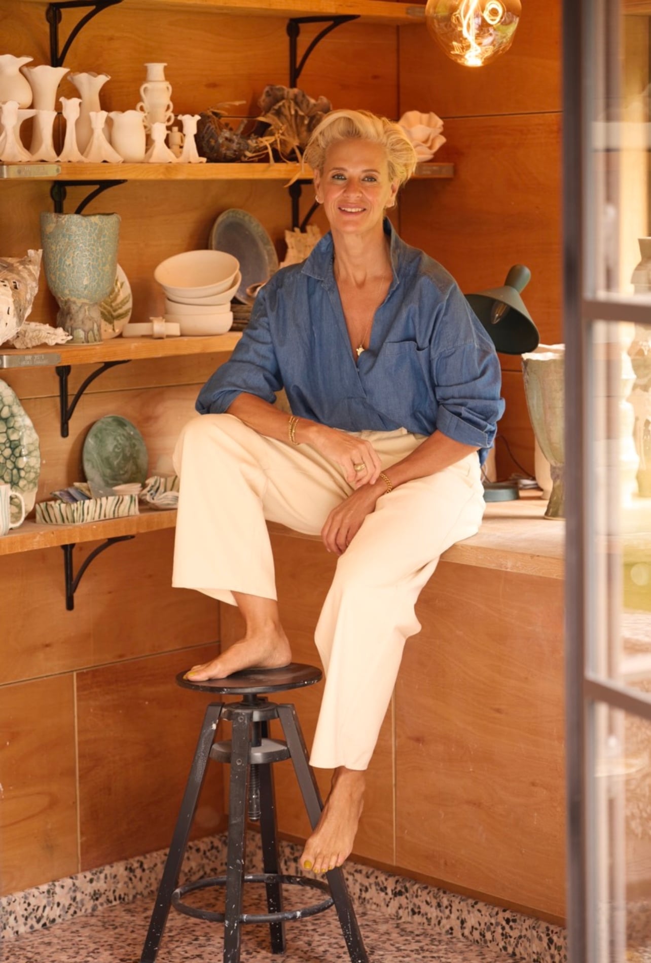 A portrait of Deborah Brett in her studio in London surrounded by ceramics