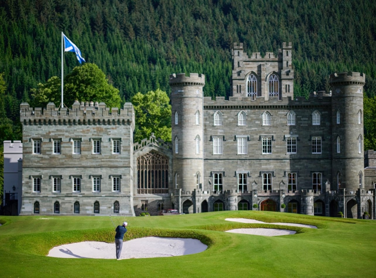 An exterior shot of someone golfing outside the grand Taymouth Castle