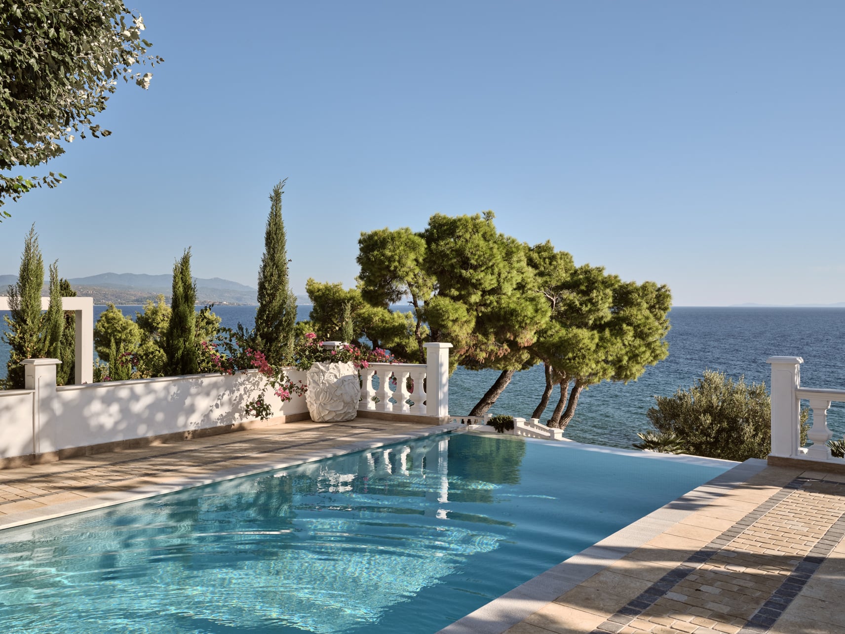 Pool and ocean view surrounded by green trees at Mandarin Villa