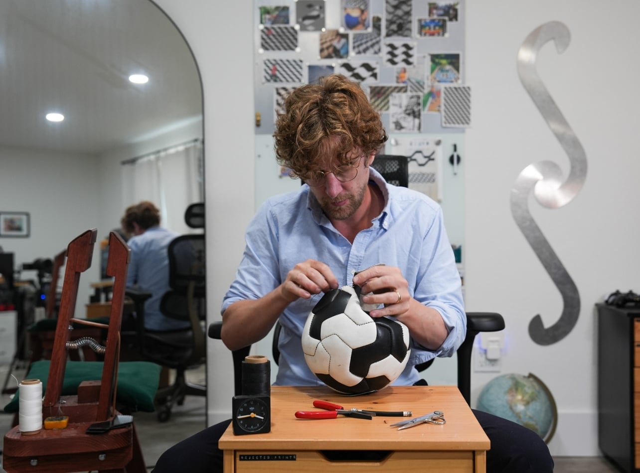 Jon Paul Wheatley sewing a white and black soccer ball