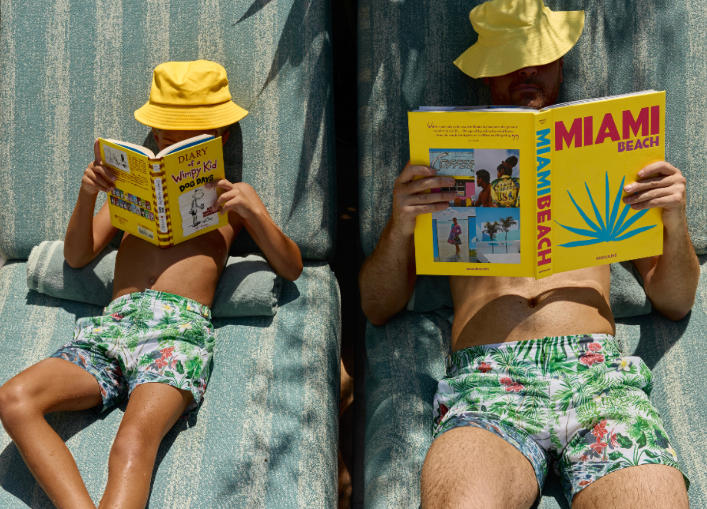 A father and son reading books on beach chairs