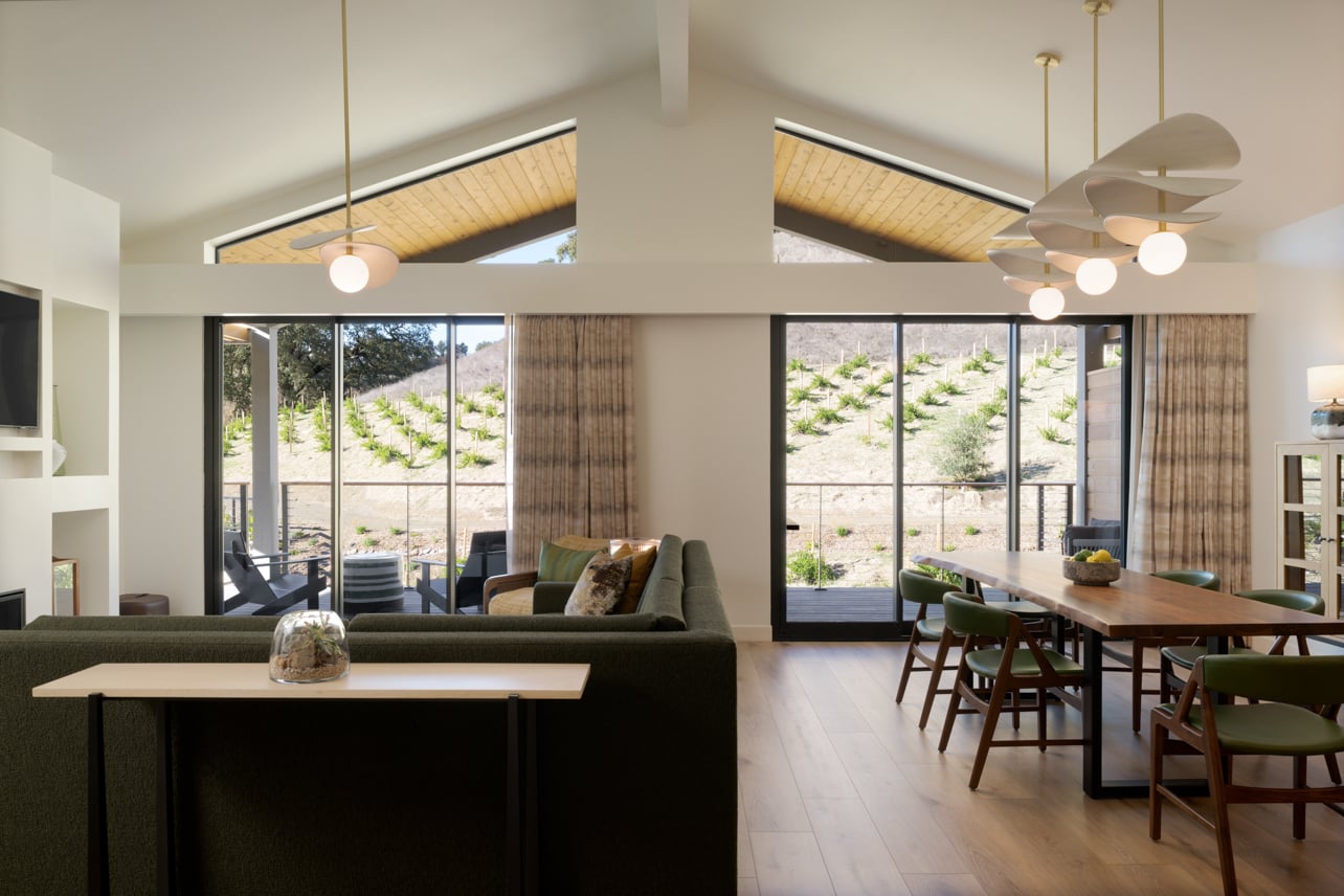 An interior of a living room with a green sofa in the Appellation two-bedroom suite