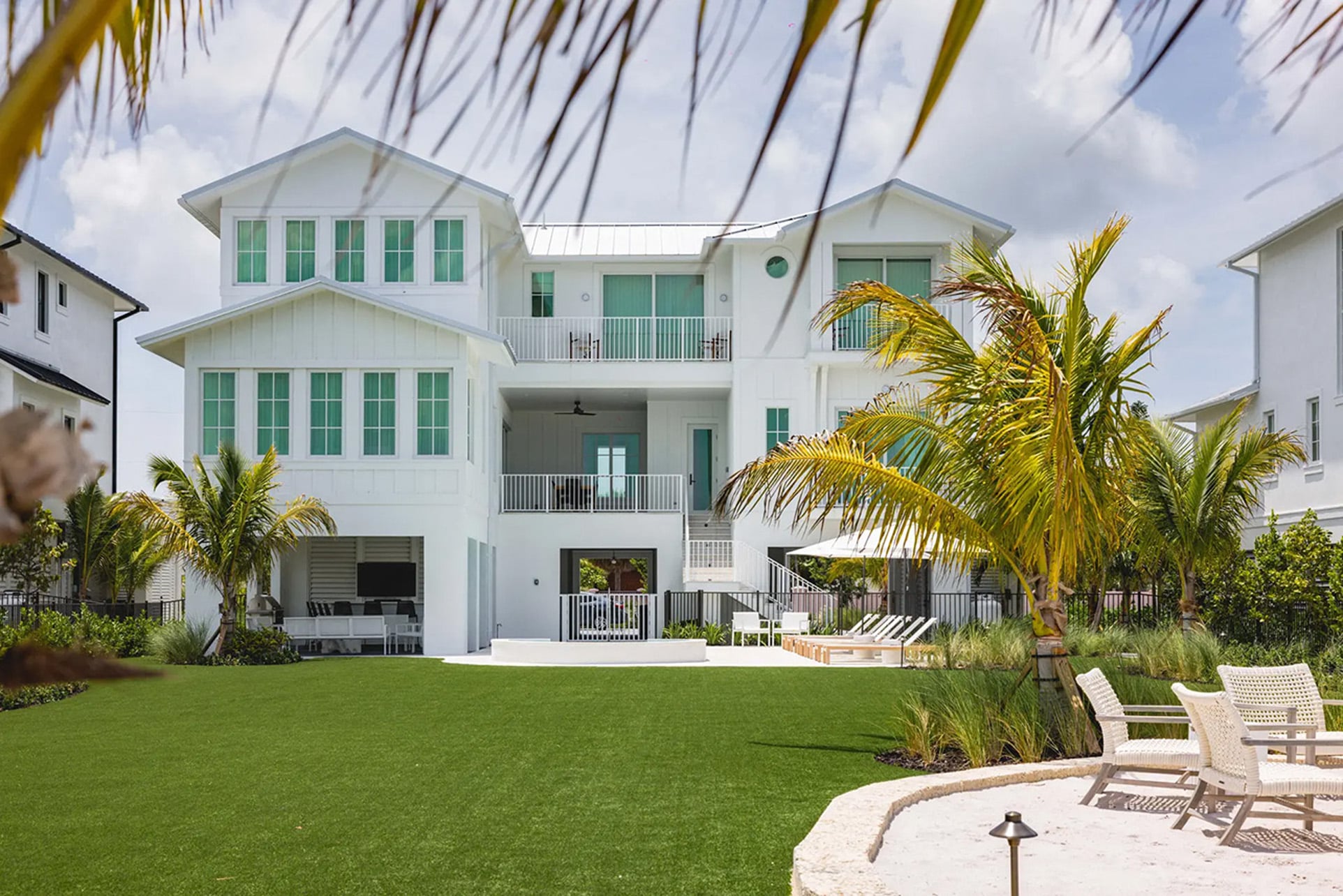 An exterior of a villa with a green lawn and seating area
